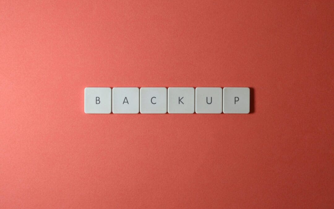 Free Close-up of keyboard keys spelling 'BACKUP' placed on a coral-colored surface. Stock Photo